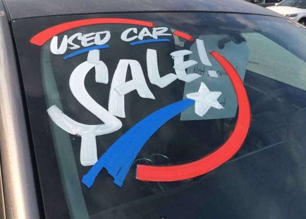 Hand-painted windshield message advertises a used car sale