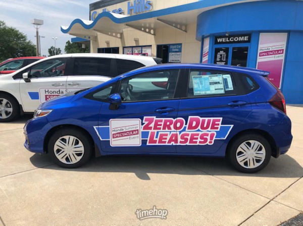 Blue car with sign advertising financing options at a car dealership.