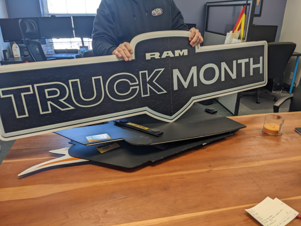 Employee holding "RAM Truck Month" magnetic vehicle sign